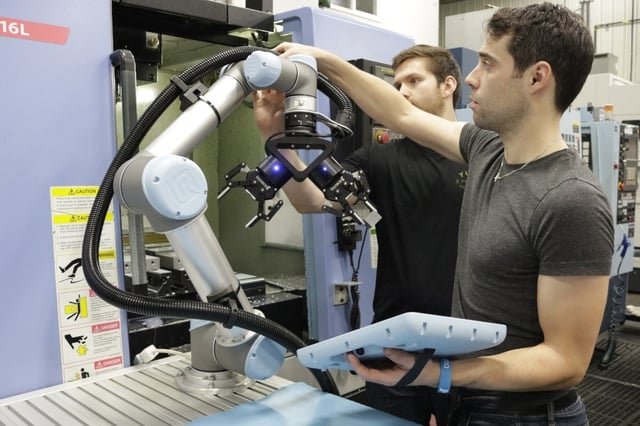 An operator is setting-up a UR cobot with a dual 2F-!$) gripper mounted on it for machine tending application