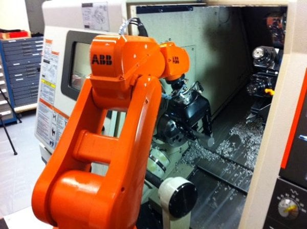 A robot arm loading a CNC lathe with a cylindrical part
