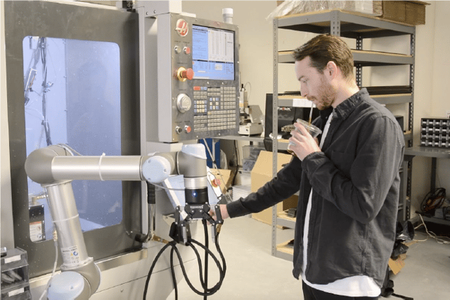 An operator is easily setting up a UR cobot with a 2F-140 to automate his CNC machine