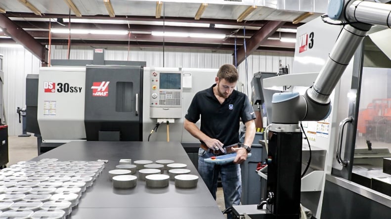 Person working with a collaborative robot in front of a Haas machine