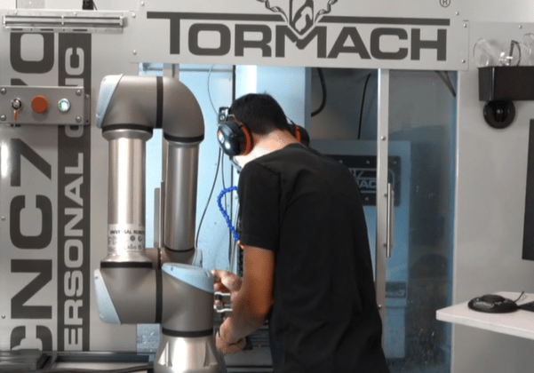 Trabajador que realiza una tarea de ensamblaje con un cobot en una planta de fabricación