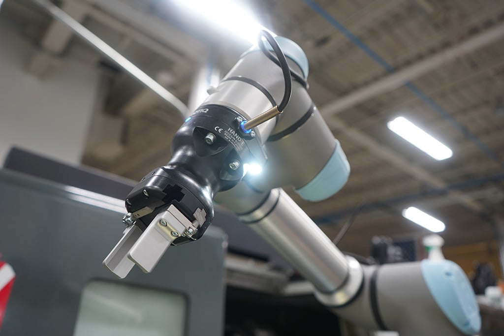 A Robotiq Hand-E gripper mounted with a Robotiq Wrist Camera on a UR robot arm for machine tending application