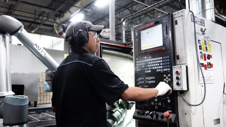 Operator operating a CNC machine beside a collaborative robot