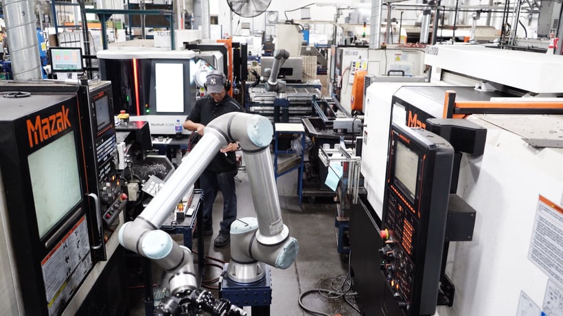 Worker in the middle of many Mazak CNC machines, with collaborative robot.
