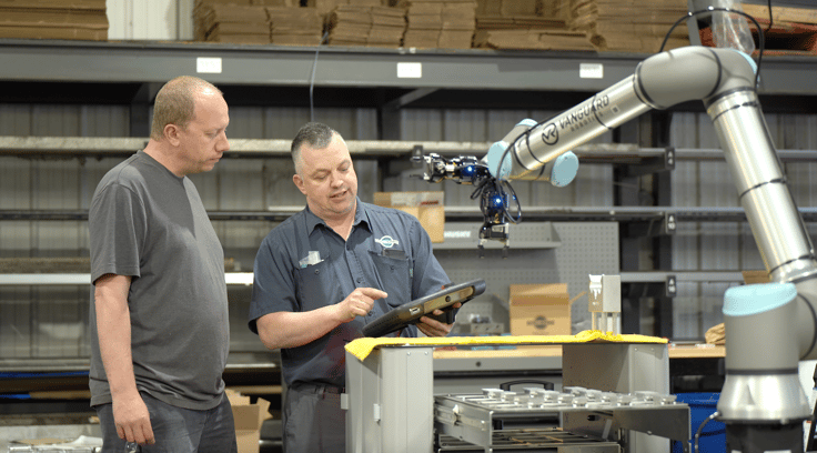 Workers programming a robot in a cnc machining environement