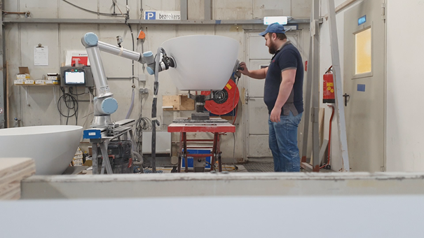 Worker using the robotiq sanding kit with Universal robots to sand a bath