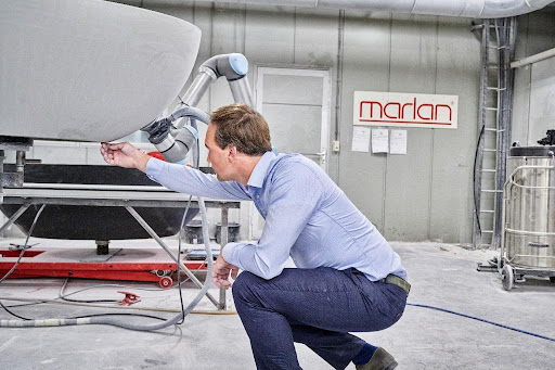 Worker using a universal robots and Robotiq sanding kit to perform a sanding task