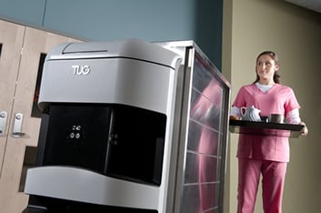 Women holding a tray near a hospital security robot