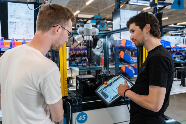 Operator teaching a colleaghe how tu use robots for screw fastening