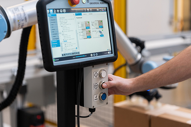 Worker using the Robotiq Palletizing Solution PE Series to accomplish material handling task