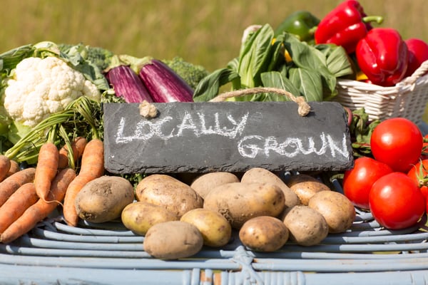 Organic vegetables on a stand at a farmers market with a sign reading locally grown