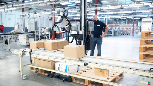 Worker working beside a Robotiq palletizing Solution