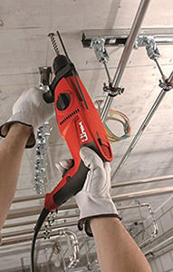 Worker drilling anchor holes on a ceiling