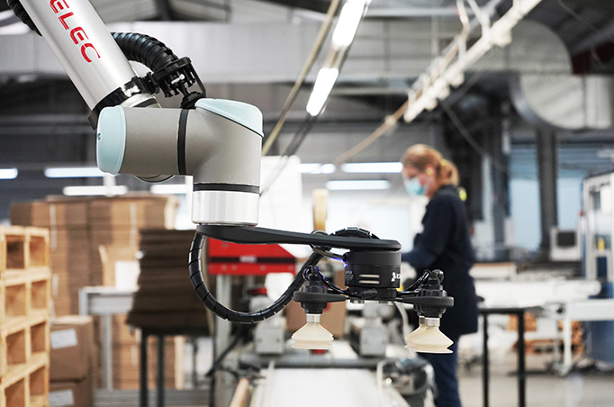 Employee working beside a robot to accomplish palletizing tasks in a manufacture