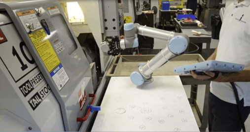 An operator using a 2F-85 Robotiq gripper mounted on a UR cobot for machine tending application